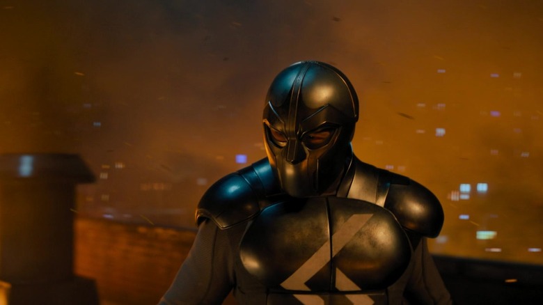Sylvester Stallone's Joe Smith stands in his superhero costume surrounded by fire in Samaritan