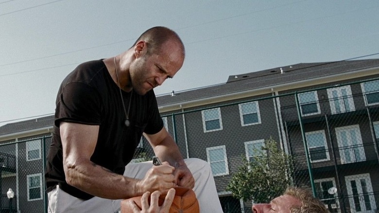 Lee Christmas holding a basketball down on a roughed up guy in The Expendables