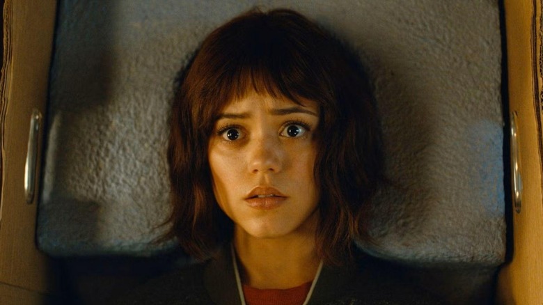 Jenna Ortega as Kalra laying in a box with wide eyes in Klara and the Sun