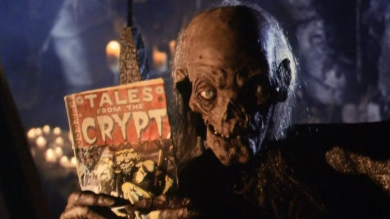 The Crypt Keeper holds up a Tales From the Crypt comic book
