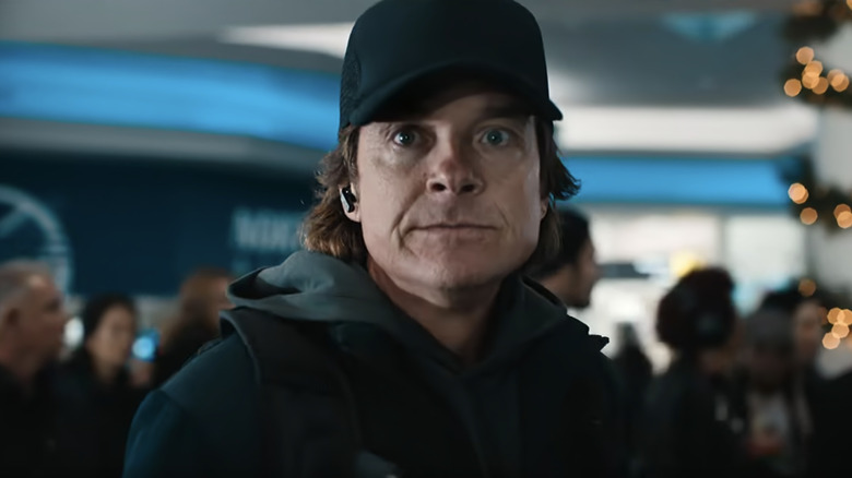 Jason Bateman's The Traveler looks surprised in closeup as he stands in an airport in Carry-On