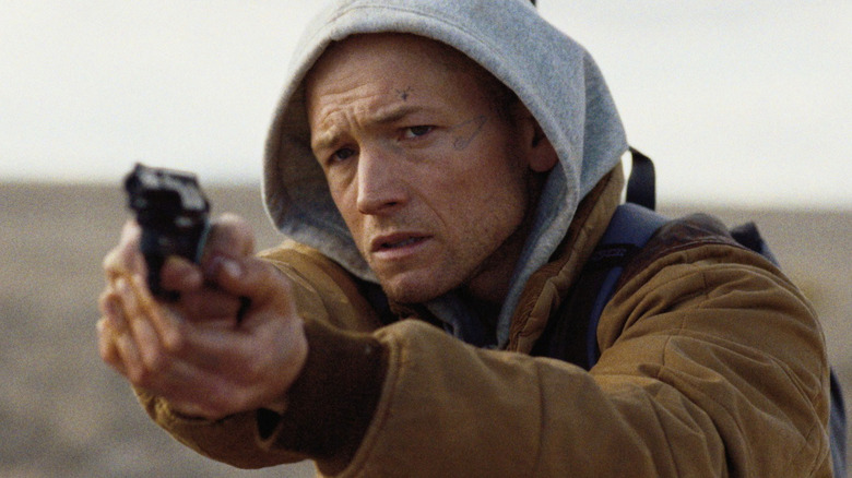 Ela Rasi Shotgun - Nate (Taron Egerton) segura a lama