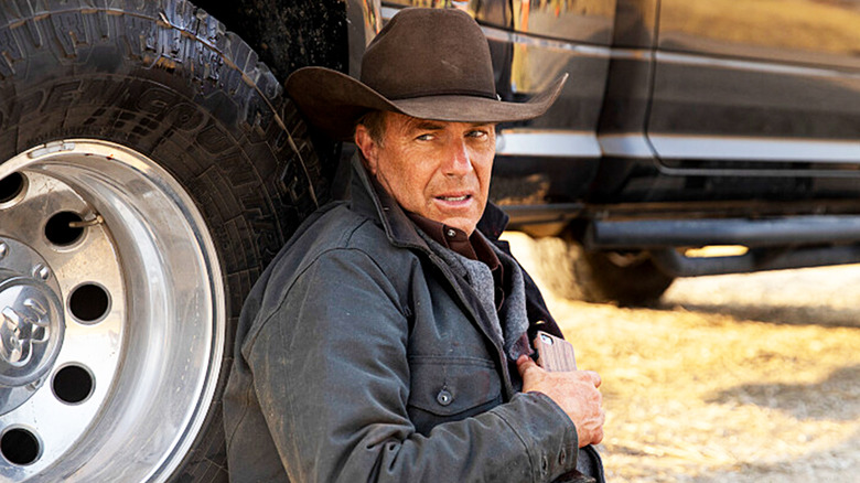 Kevin Costner's John Dutton lays against a car tire in Yellowstone