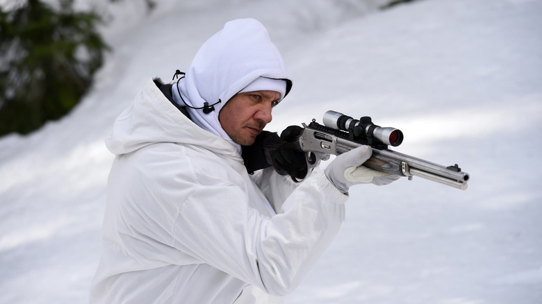 Jeremy Renner as Cory Lambert dressed in white hunting gear and aiming a rifle in Wind River