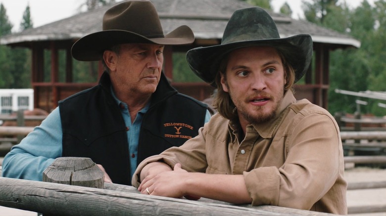 Kevin Costner as John Dutton and Luke Grimes as Kayce Dutton leaning on a fence on Yellowstone