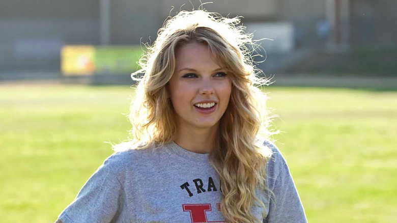 Felicia (Taylor Swift) smiling and standing in front of a grassy surface in "Valentine's Day"