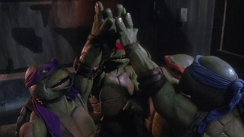 Raph, Leo, Mikey, and Donnie high fiving in Teenage Mutant Ninja Turtles (1990)