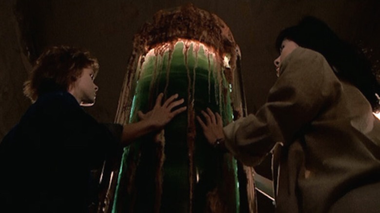 Women touching green cylinder