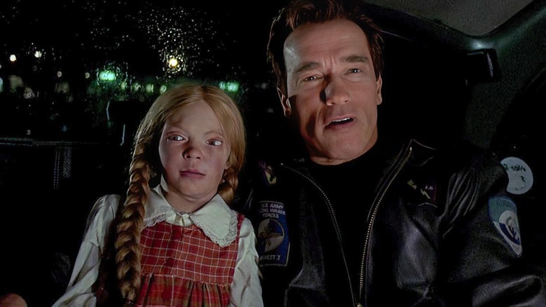 Arnold Schwarzenegger als Adam Gibson die een pop vasthoudt in The Sixth Day