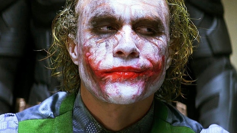 The Joker in an interrogation room with Batman standing behind him in The Dark Knight