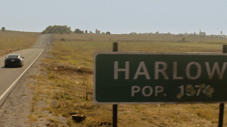 car driving on a road next to a sign for "harlow"