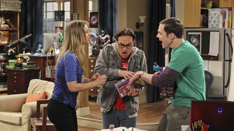 Leonard and Sheldon fighting over an action figure with Penny watching on The Big Bang Theory