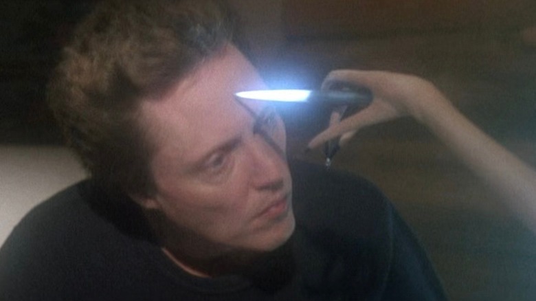 A long pink alien arm holds a glowing probe to the forehead of Christopher Walken as Whitley, in Communion