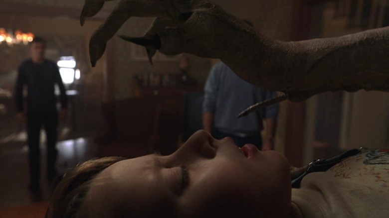 An alien holds its clawed hand over the face of Rory Culkin as Morgan, in Signs