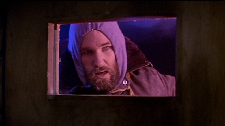 A bundled-up Kurt Russell as RJ, peering in a window, in The Thing