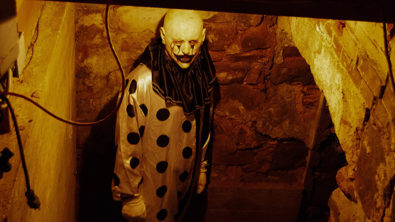 Joe Bandelli as the clown standing in an unfinished basement in Hell House LLC