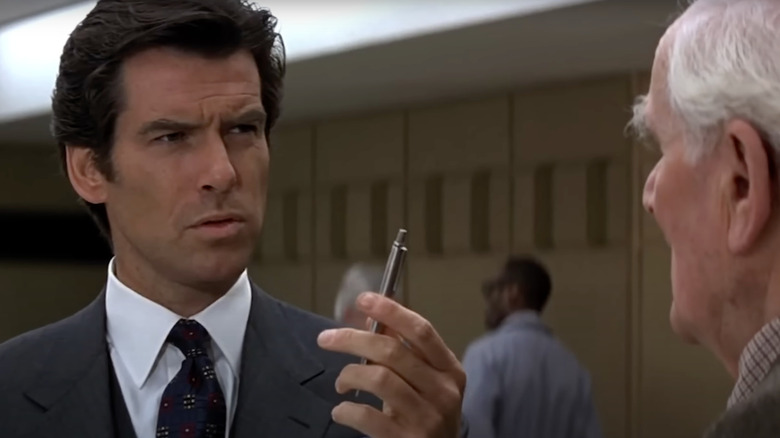 Pierce Brosnan as James Bond holds an explosive pen in front of Desmond Llewelyn in GoldenEye