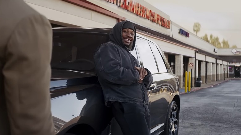 Jonathan Majors leaning against Rolls Royce