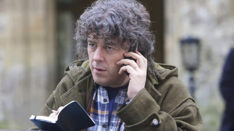 Jonathan Creek (Alan Davies) takes notes while on the phone in Jonathan Creek