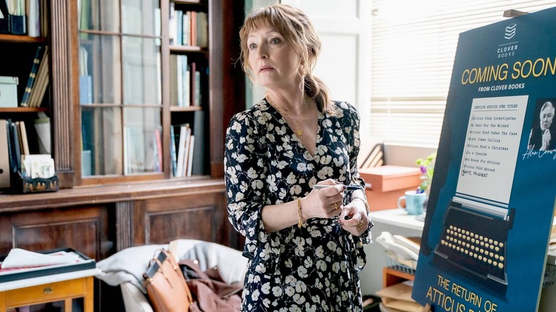 Susan Ryeland (Lesley Manville) looks back while writing on a poster in a library in Magpie Murders