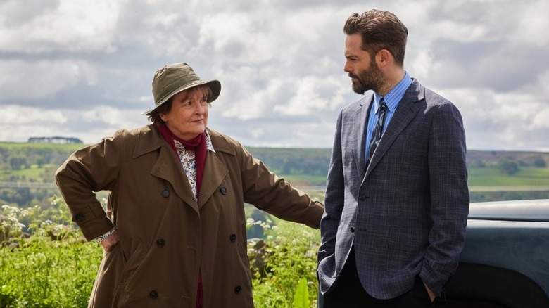 Vera Stanhope (Brenda Blethyn) and Joe Ashworth (David Leon) glance at each other by a parked car in Vera