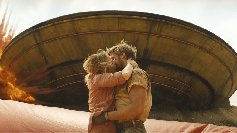 Colt Seavers (Ryan Gosling) and Jody Moreno (Emily Blunt) kissing while a prop UFO explodes behind them