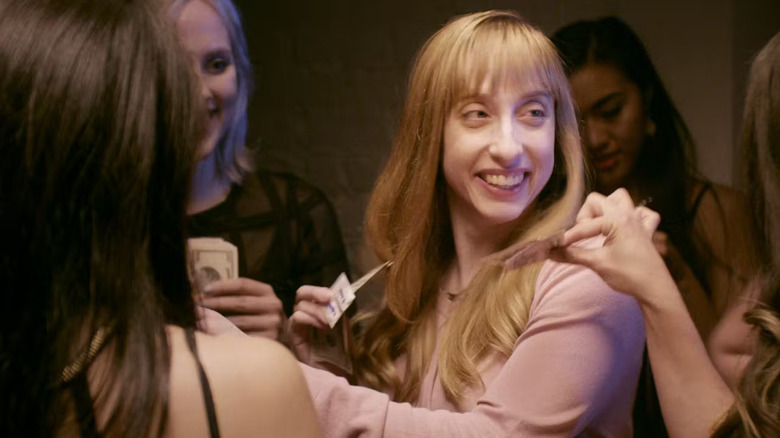 Katie Marovitch surrounded by people giving her money in Kingpin Katie
