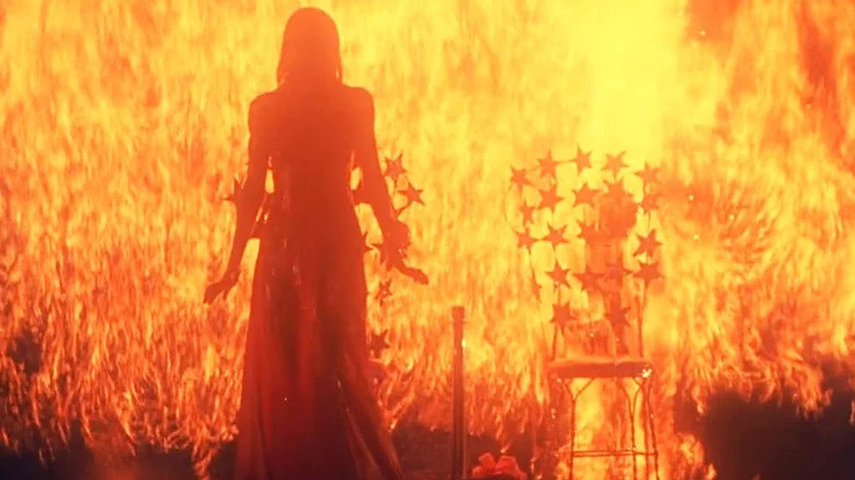 Sissy Spacek's Carrie White standing in front of a wall of flame in Carrie
