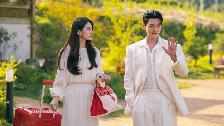 Ka Young (Bae Suzy) holds bags while watching Jinn (Kim Woo-bin) raise his hand in Genie, Make a Wish