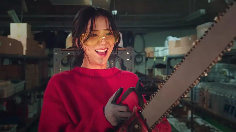 Kang Young-ju (Jisoo) happily revs a chainsaw in Newtopia