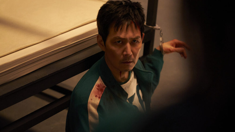 Seong Gi-hun (Lee Jung-jae) is handcuffed to a bed frame in Squid Game