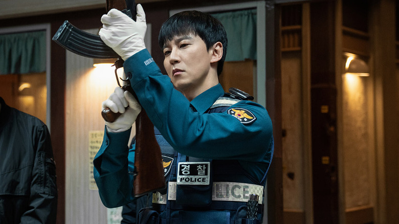 yi-do (Kim Nam-gil) inspects an assault rifle in Trigger