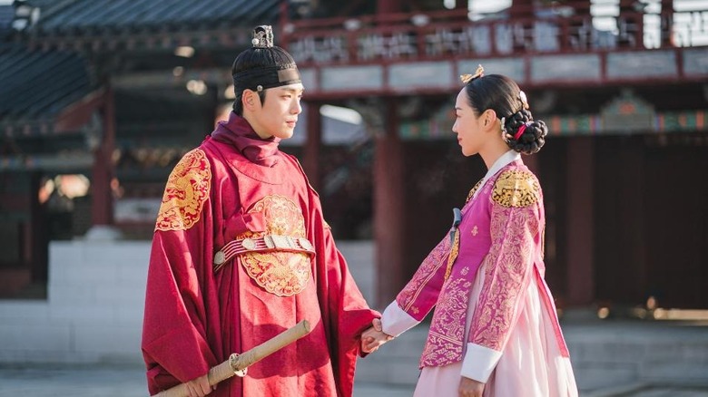 King Cheoljong (Kim Jung-hyun) holds hands with Queen Cheorin (Shin Hye-sun) by a palace in Mr. Queen
