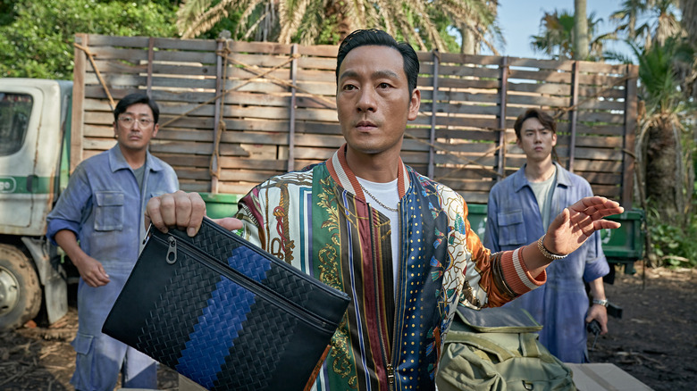 Choi Chang-ho (Park Hae-soo) holds up a bag in Narco-Saint