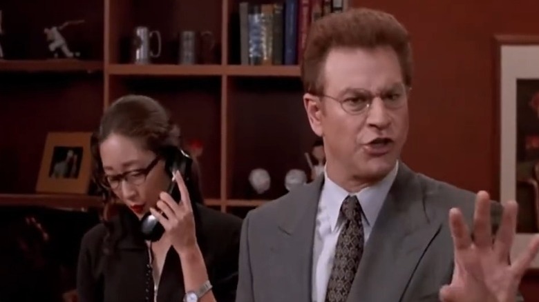 Robert Wuhl as Arliss Michaels speaking angrily while Sandra Oh as Rita Wu talks on the phone behind him on Arliss