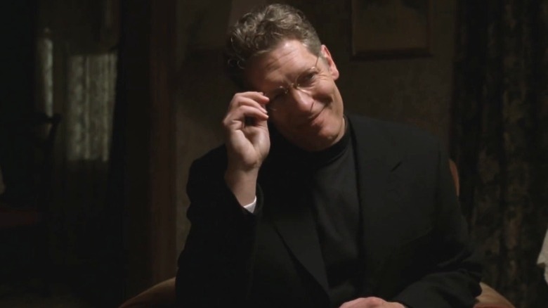 Clancy Brown as Brother Justin Crowe smiling and pinching his glasses on Carnivale