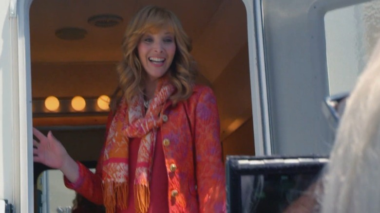 Lisa Kudrow as Valerie Cherish standing at the door of a trailer and speaking to a camera crew on The Comeback