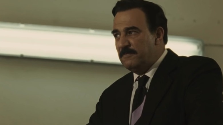 Yigal Naor as Saddam Hussein standing in front of a fluorescent light on House of Saddam