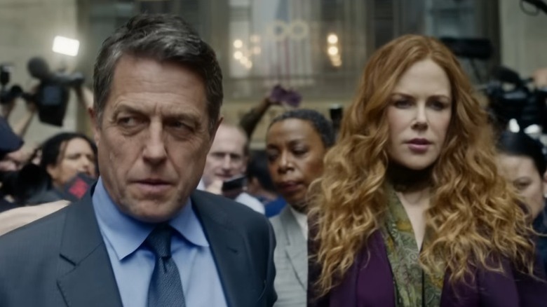 Hugh Grant as Jonathan Fraser and Nicole Kidman as Grace Fraser walking out of a courtroom while surrounded by journalists and photographers on The Undoing