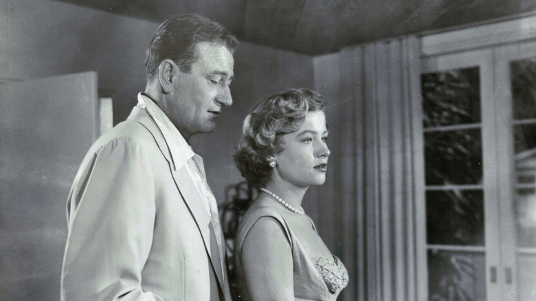 John Wayne as Jim McLain, embracing Veda Ann Borg as Madge from behind in Big Jim McLain.