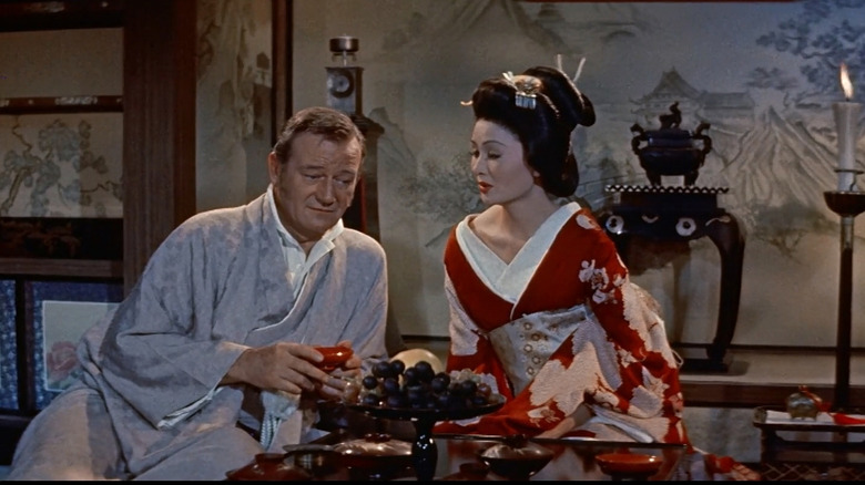 A robed John Wayne as Townsend Harris, sitting with Eiko Ando as Okichi in The Barbarian and the Geisha.