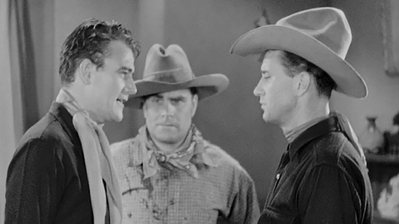 John Wayne as Chris Morrell arguing with two outlaws in 'Neath the Arizona Skies.