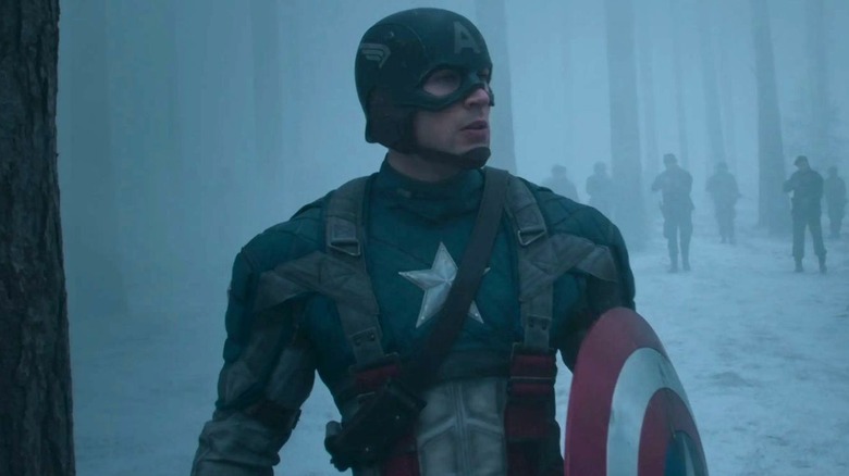 Chris Evans as Captain America stands outside with soldiers behind him in Captain America: The First Avenger