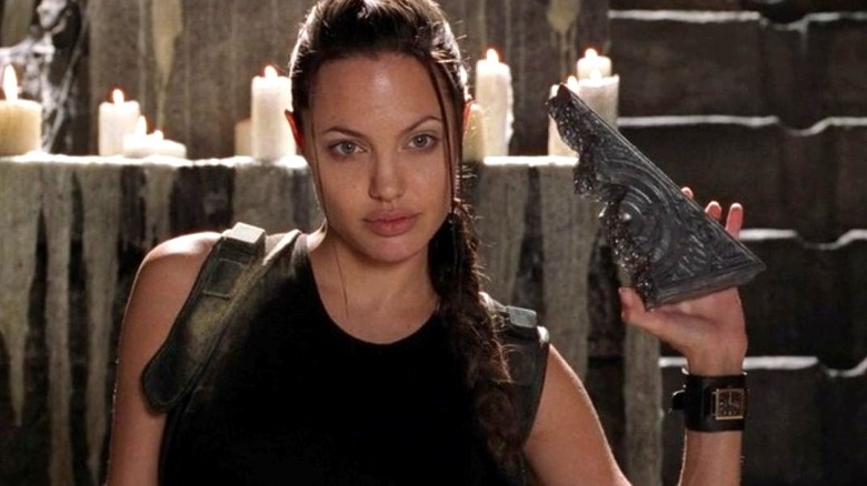 Angelina Jolie as Lara Croft holds half of the Triangle of Light and looks ahead in Lara Croft: Tomb Raider