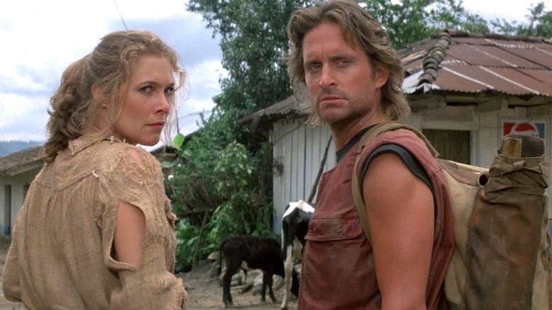 Kathleen Turner as Joan Wilder stands next to Michael Douglas as Jack Colton outside in Romancing the Stone