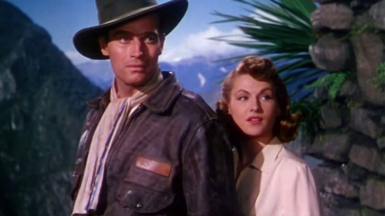 Charlton Heston as Harry Steele stands outside next to Elena Antonescu as Nicole Maurey in Secret of the Incas