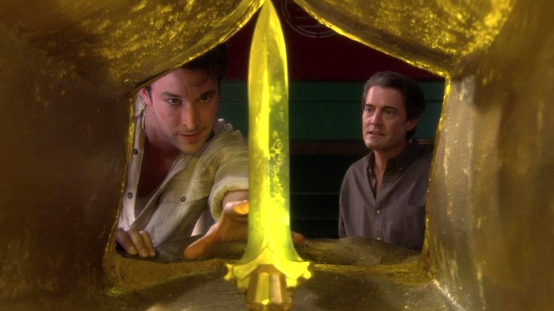 Noah Wyle as Flynn Carsen reaches for a gold spear while standing next to Kyla MacLachlan as Edward Wilde in The Librarian: Quest for the Spear