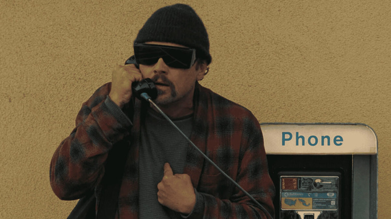 Leonardo DiCaprio as Bob using a payphone in One Battle After Another