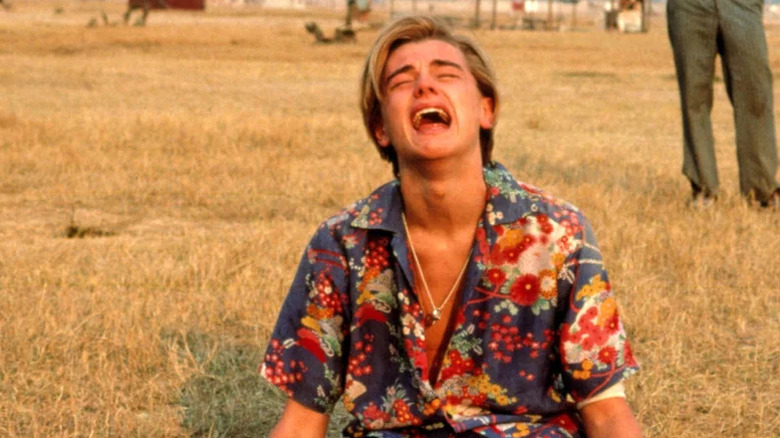 Leonardo DiCaprio as Romeo kneeling on the ground crying with mouth open and head up in Romeo + Juliet