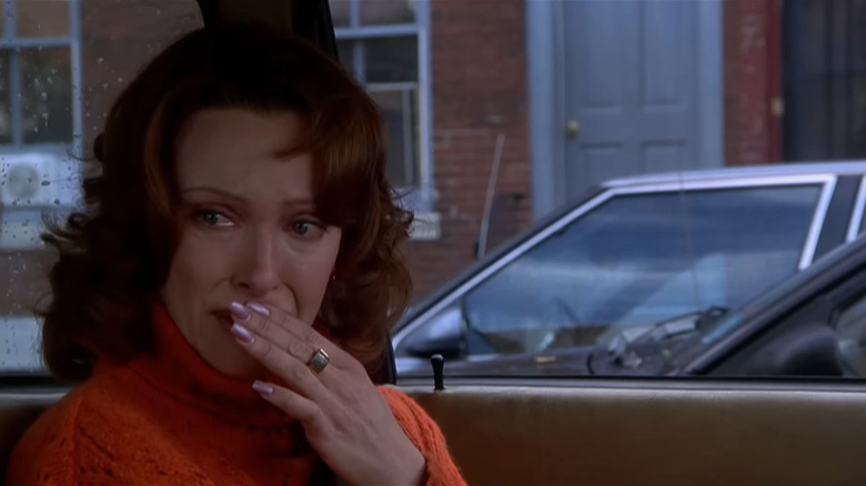 Toni Collette as Lynn sitting in car with orange sweater and pink nails with tears in her eyes in The Sixth Sense